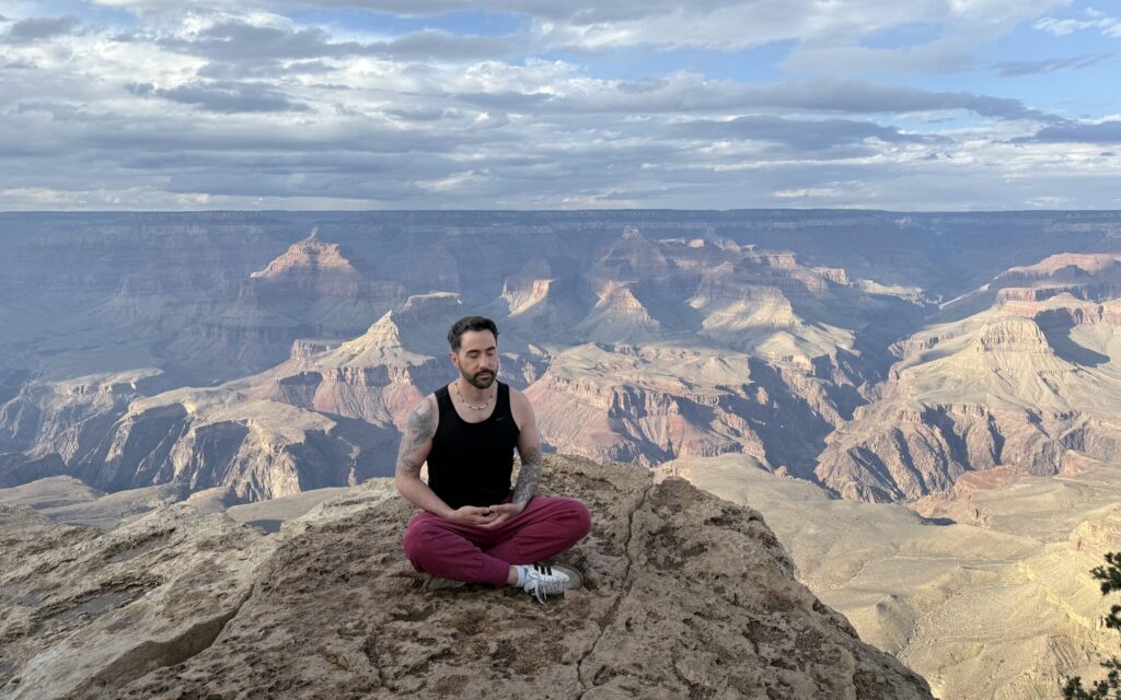 Cory Verissimo in meditation posture on the ledge at the grand canyon